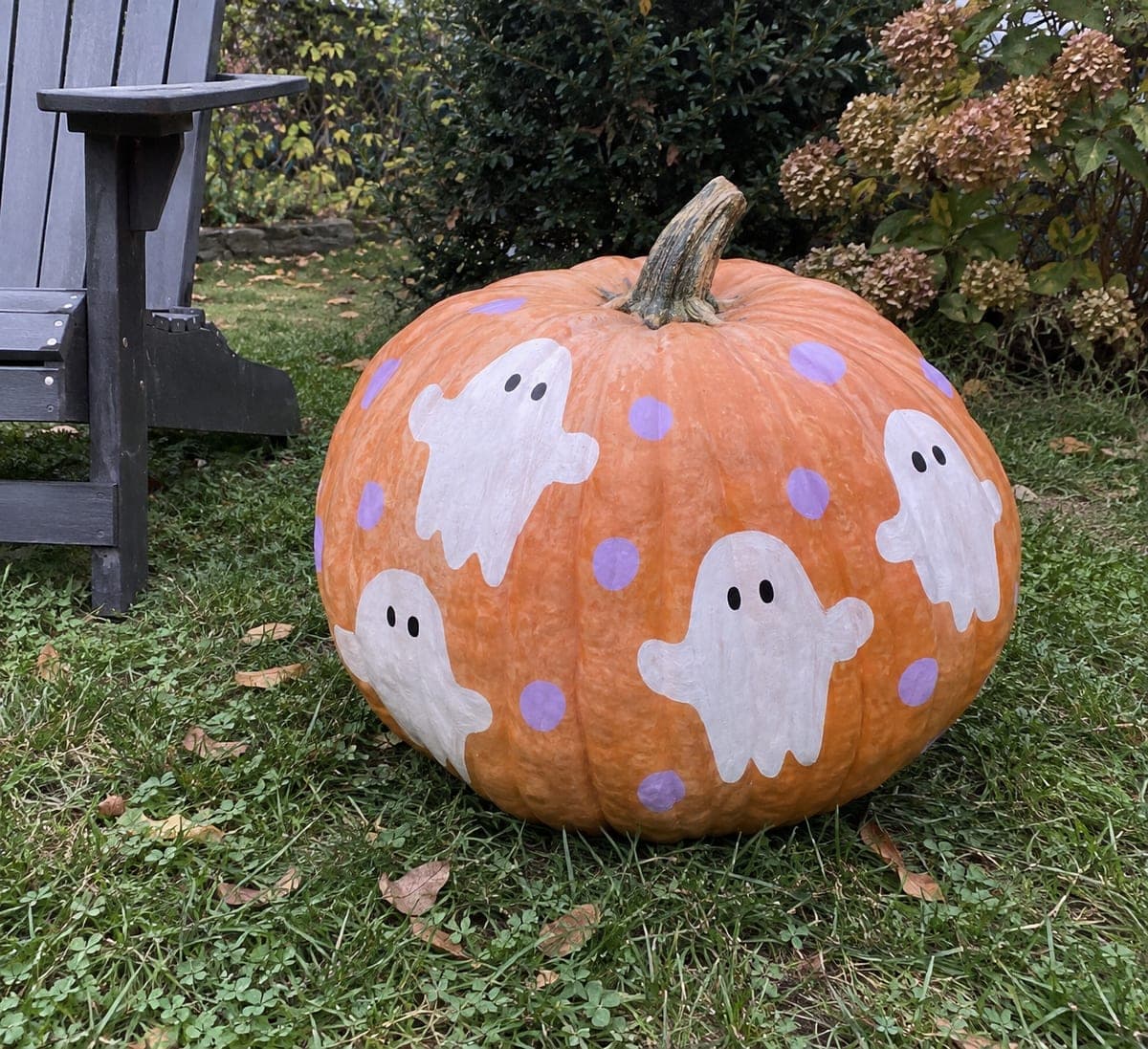 Ghost-Painted Giant Pumpkin Beside a Garden Chair