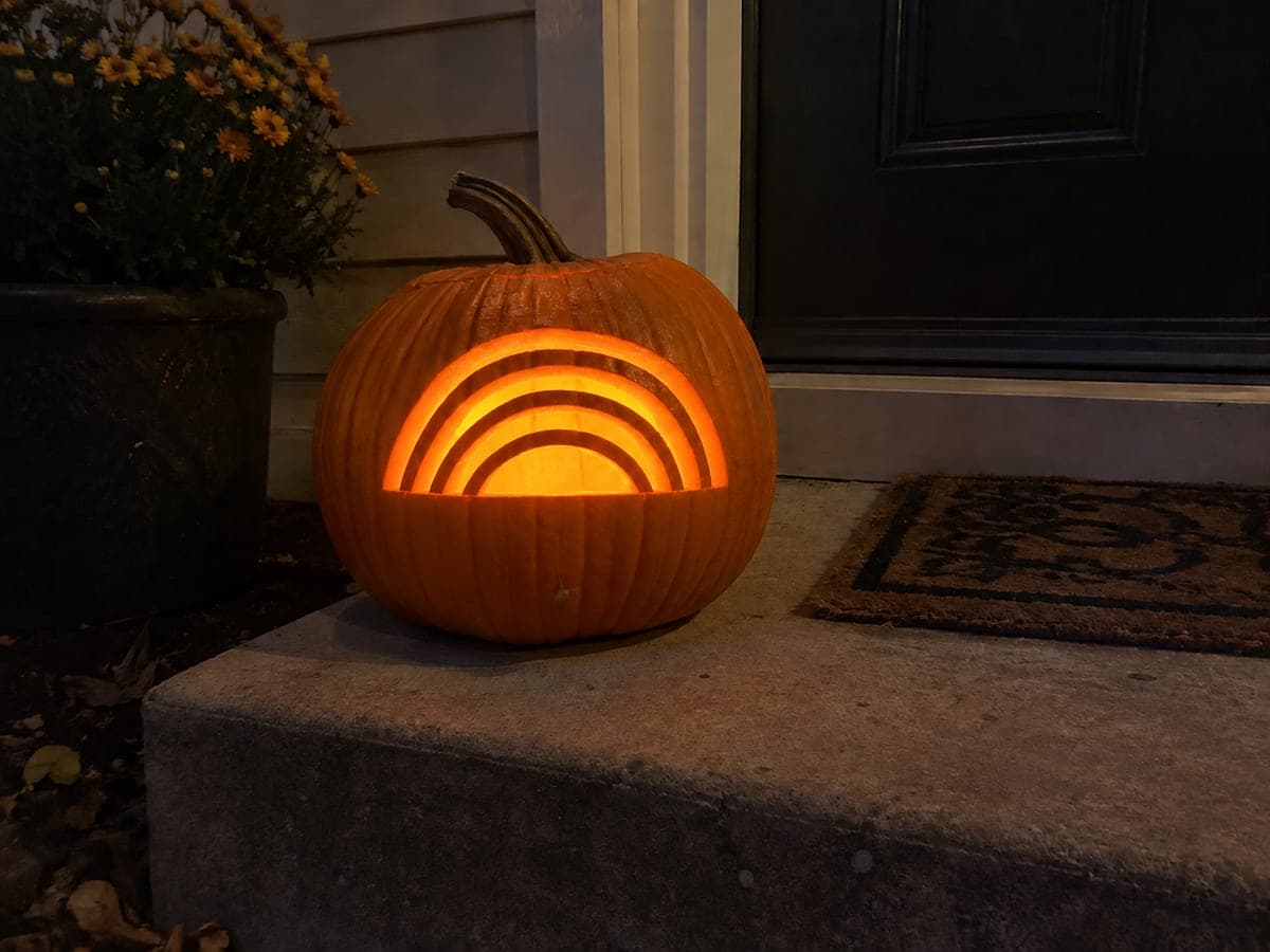 Rainbow Arc Cutout Pumpkin Glowing on a Dark Porch