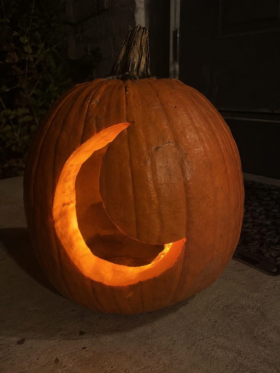Single Glowing Crescent Moon Pumpkin on a Concrete Porch